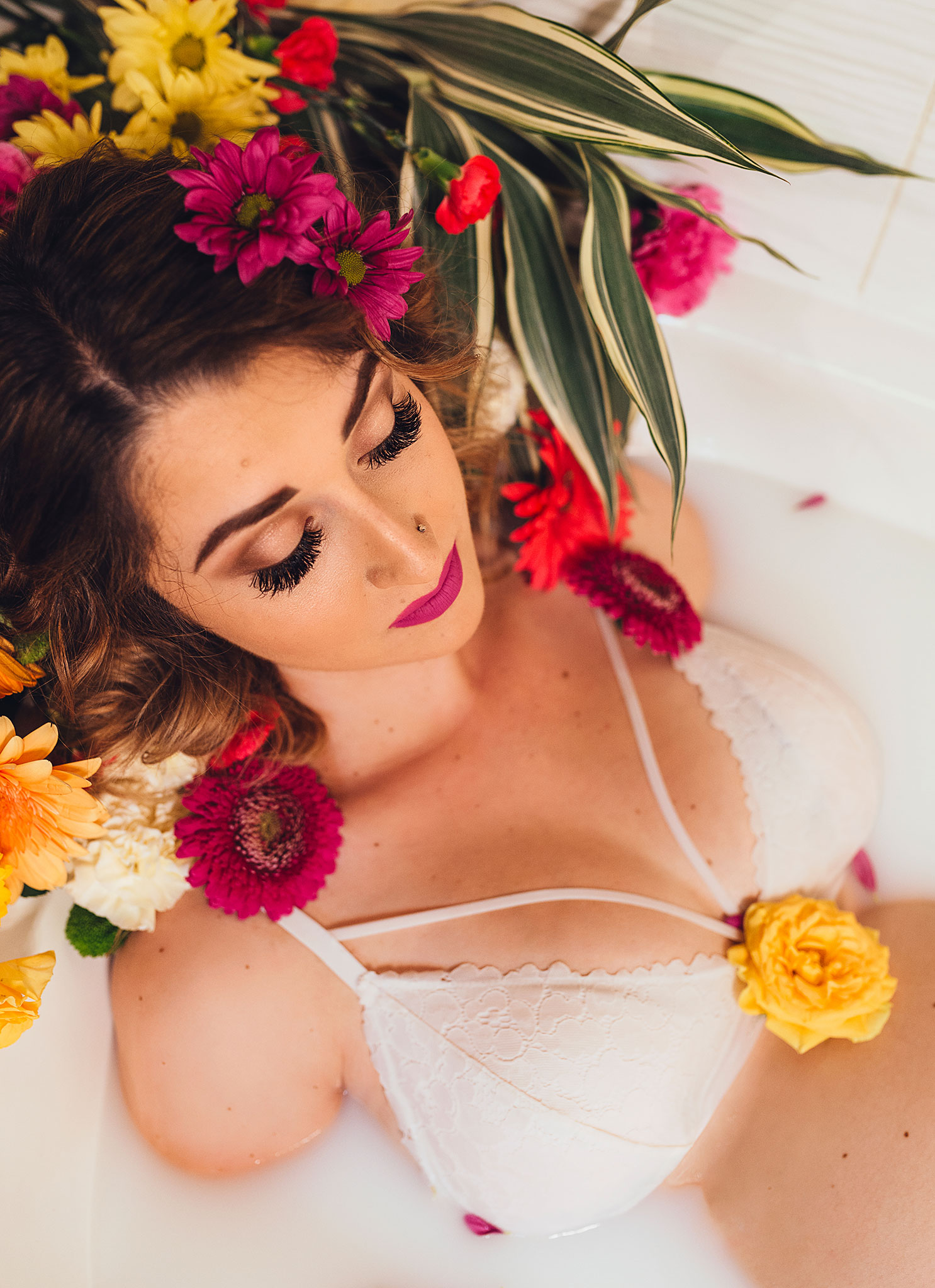 Milk bath maternity photography with brightly coloured flowers and makeup.