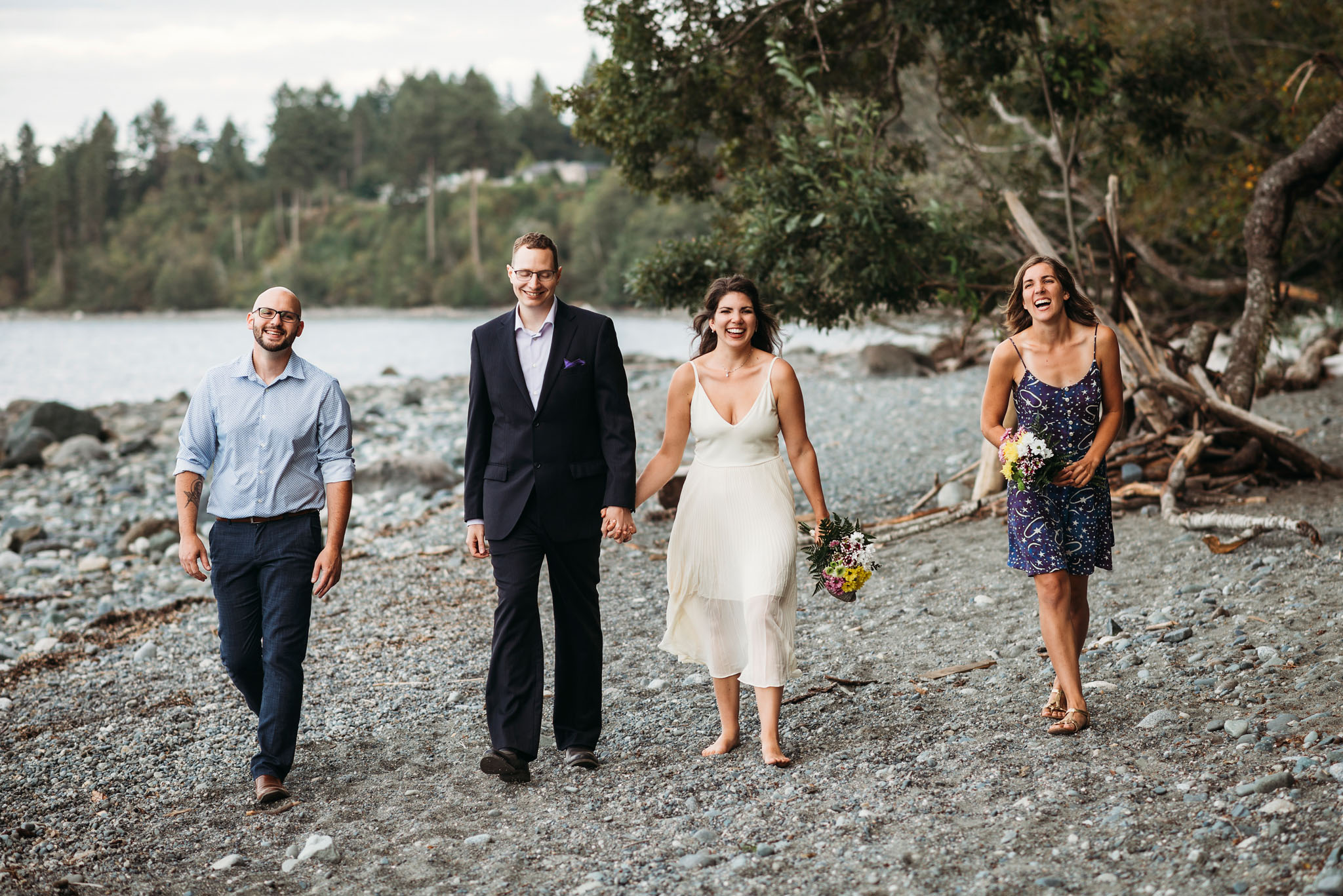 Bride and groom walking along beach with their two witnesses after eloping at Seal Bay Park in the Comox Valley.