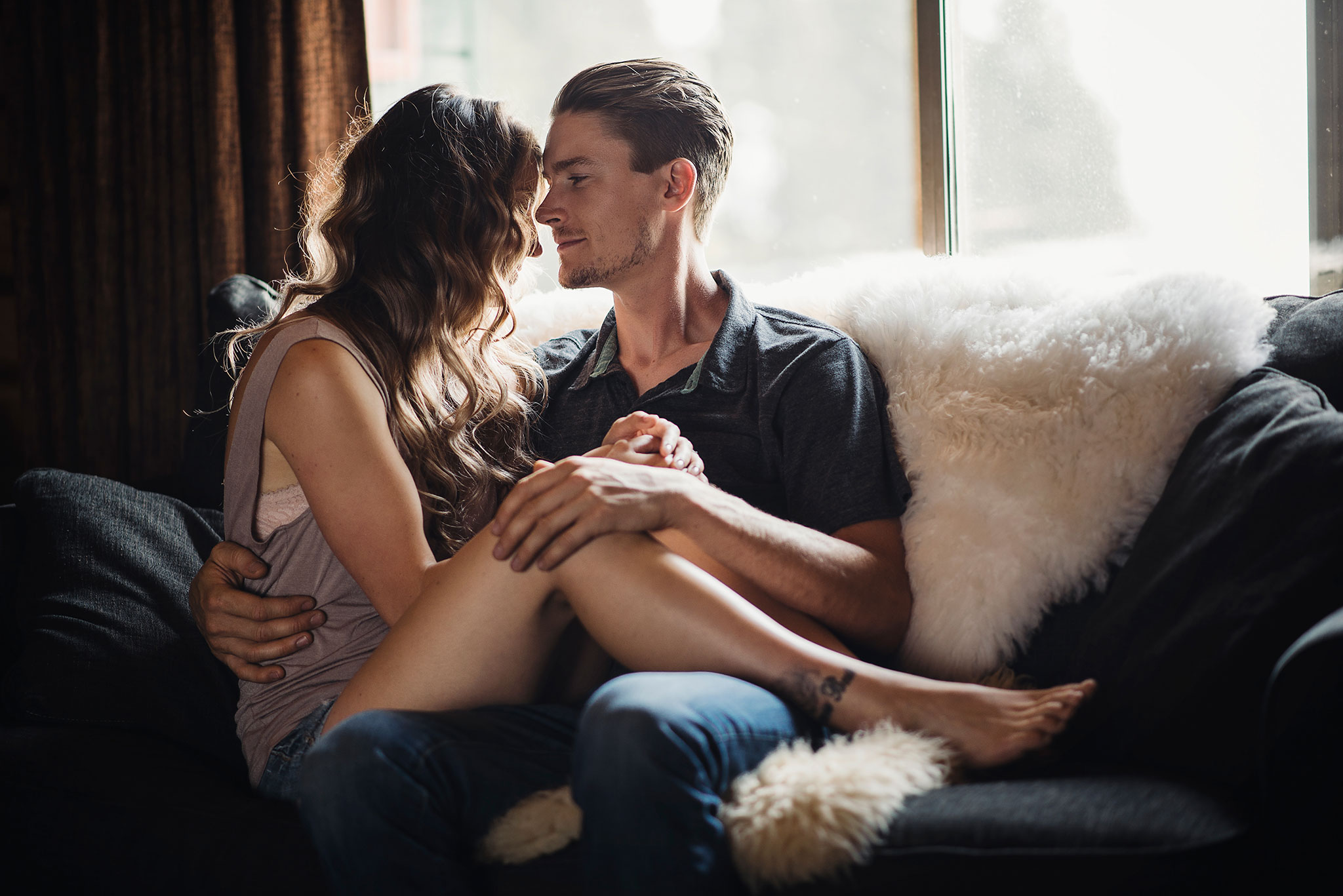 Couple snuggled together in a cozy cabin for engagement photographs.